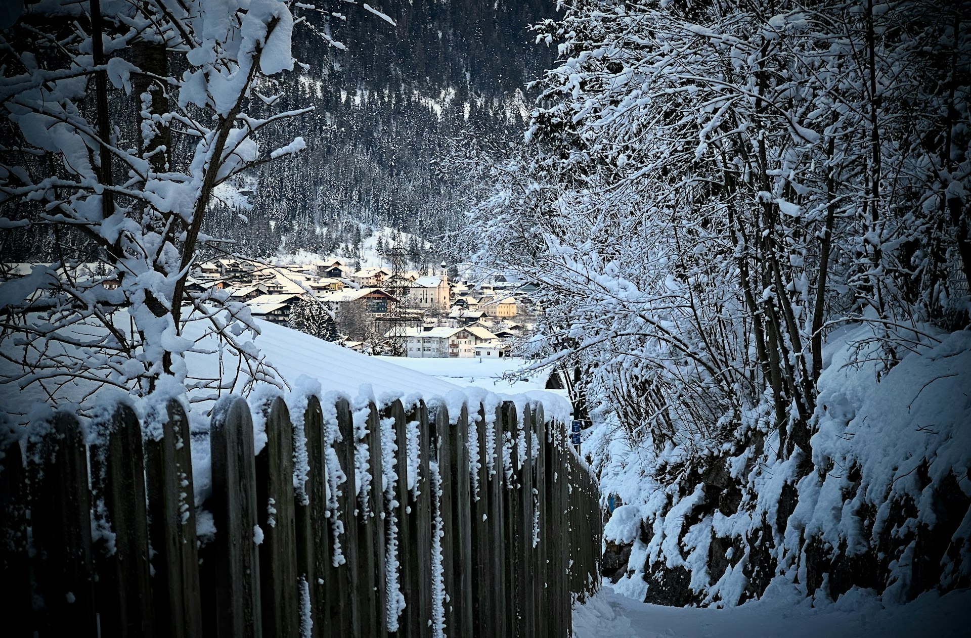 a fence is covered in snow near a village